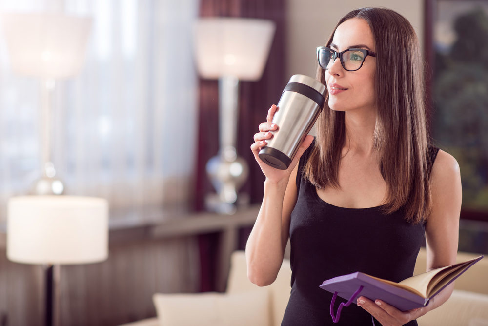 woman-dreaming-and-holding-thermo-mug